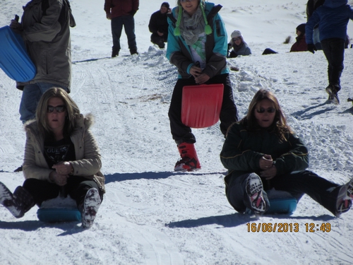 The girls kickin' up snow in their plastic bum board